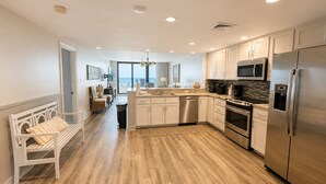 Una cocina moderna con una isla central, electrodomésticos de acero inoxidable y vistas al exterior.