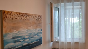 A room with a large abstract painting on the wall, a window with sheer curtains, and a patterned border along the lower edge of the wall. - A4 Beachfront apt With big Terrace and sea View (Podstrana)