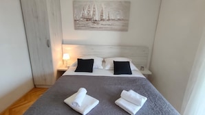 A neatly made bed with two pillows, a headboard, and a painting of sailboats on the wall. - A4 Beachfront apt With big Terrace and sea View (Podstrana)