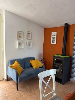 A living room with a sofa, a chair, a fireplace, and framed pictures on the wall. - Vacation home 180 mt from the sea, ideal with dogs (Tertenia)