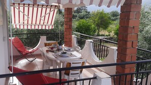 A balcony with a table, chairs, and a red chair. - Vacation home 180 mt from the sea, ideal with dogs (Tertenia)