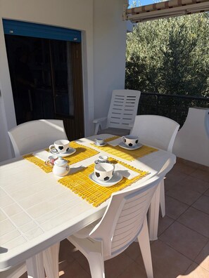 A dining table with chairs, yellow placemats, and white tableware. - Vacation home 180 mt from the sea, ideal with dogs (Tertenia)