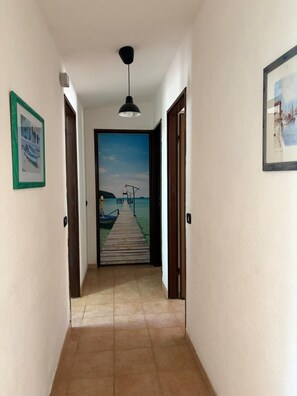 A hallway with a wooden floor leading to a door with a view of a pier and water. - Vacation home 180 mt from the sea, ideal with dogs (Tertenia)