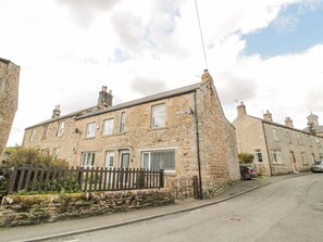 A stone building with a traditional design, featuring multiple windows and a small porch area.