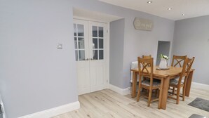 Un comedor con una mesa y sillas de madera, un radiador blanco y un cartel en la pared.
