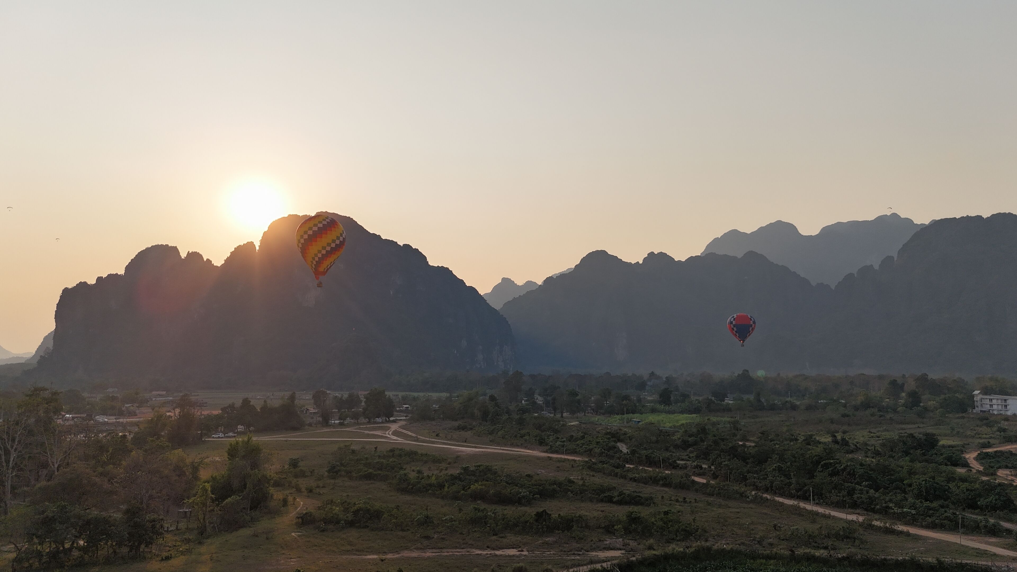 A landscape with mountains and two hot air balloons.