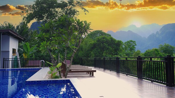 A pool area with a view of mountains and hot air balloons in the sky. - Mad Monkey  Vang Vieng (Vang Vieng)