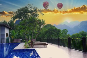 Zona de piscina con vistas a montañas y globos aerostáticos en el cielo.