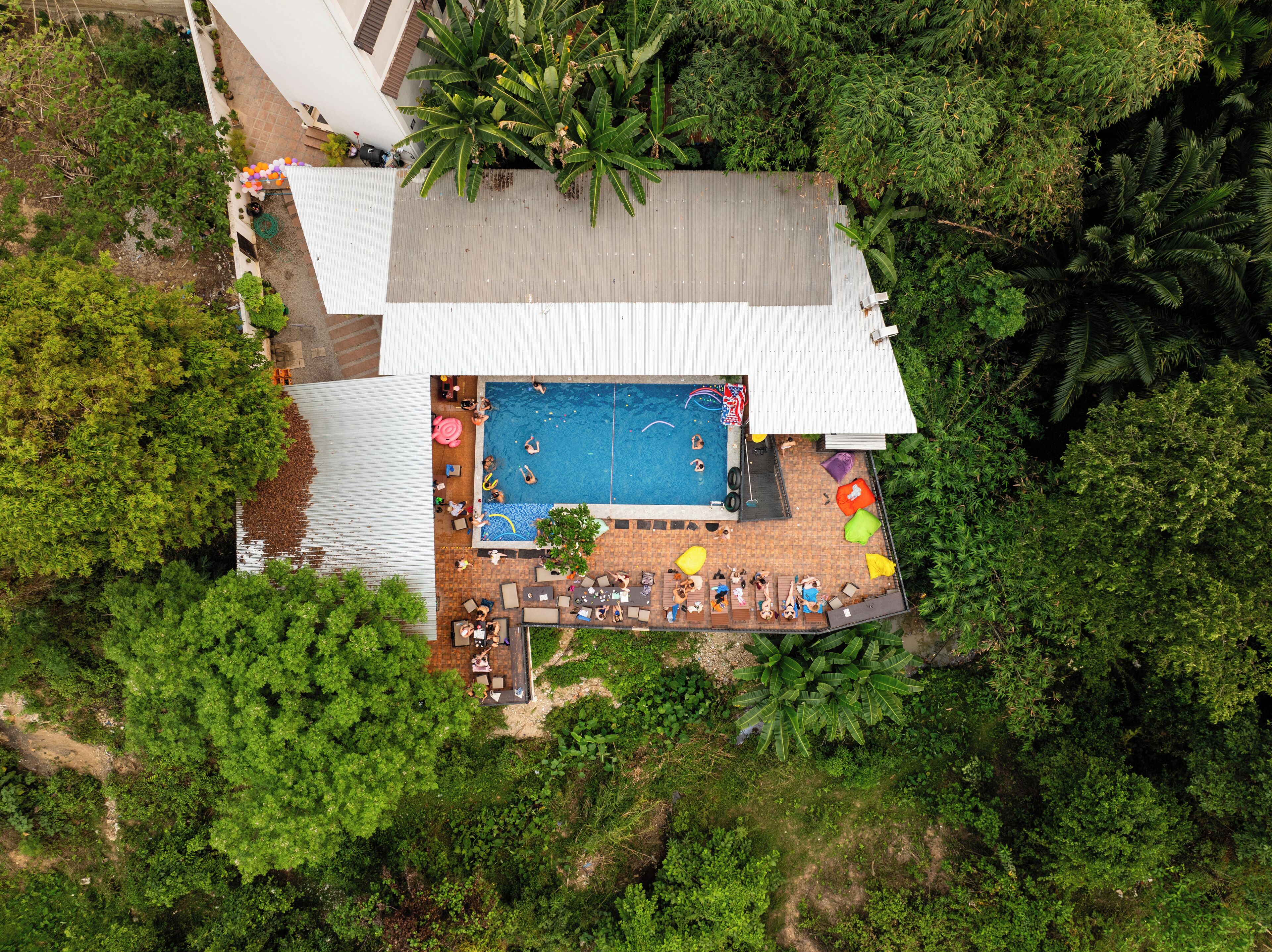 Vue aérienne d’un complexe hôtelier doté d’une piscine, d’un espace de détente et d’une végétation luxuriante.