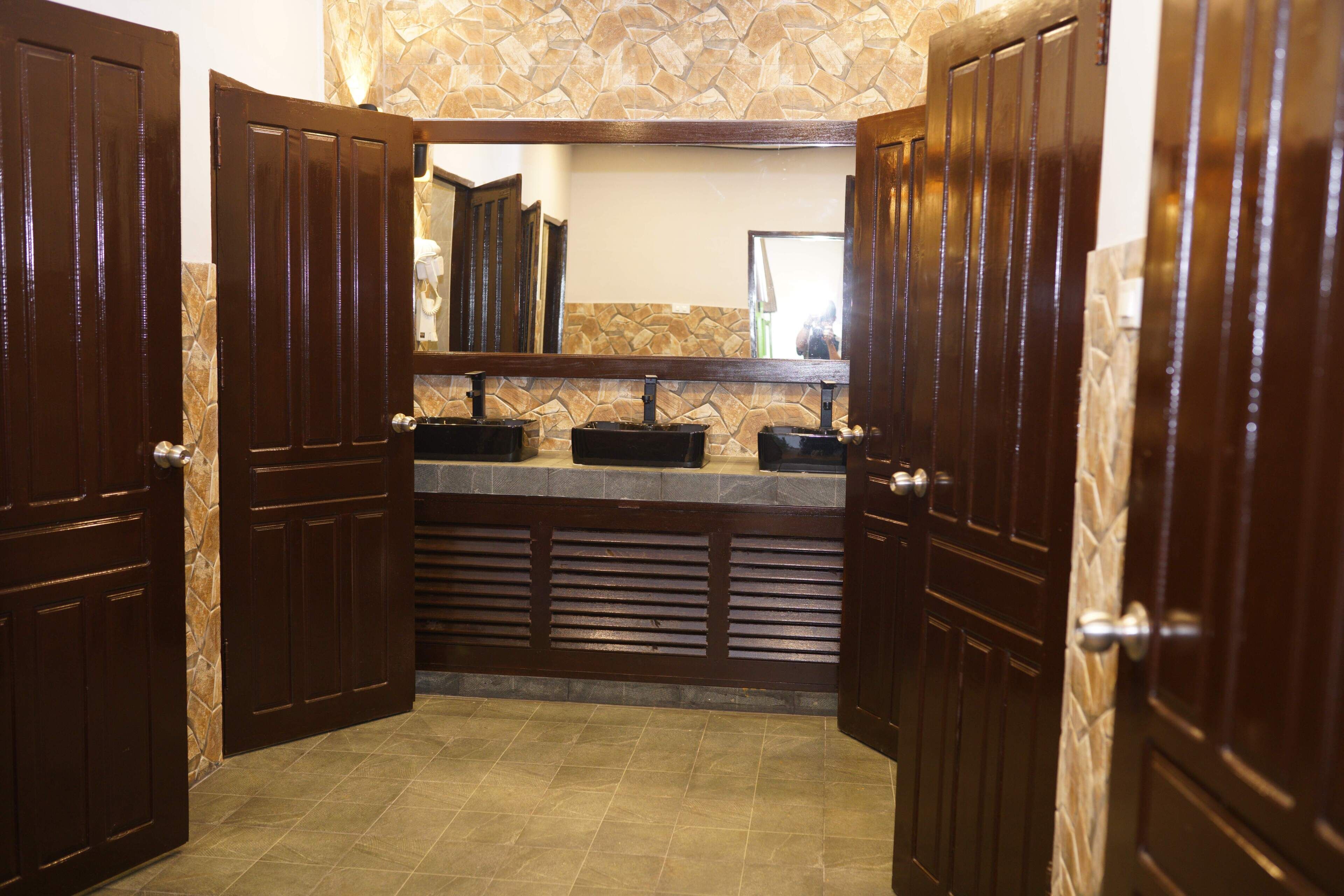A bathroom with two sinks, a mirror, and wooden doors.