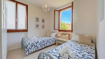 Una camera da letto con due letti, una finestra, un termosifone e una scrivania.