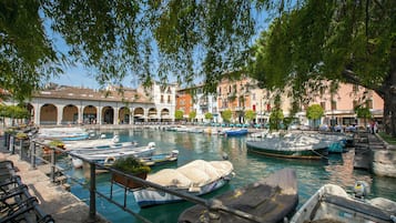 Un canal con barcos amarrados, rodeado de edificios con arcos y un árbol sobre él.