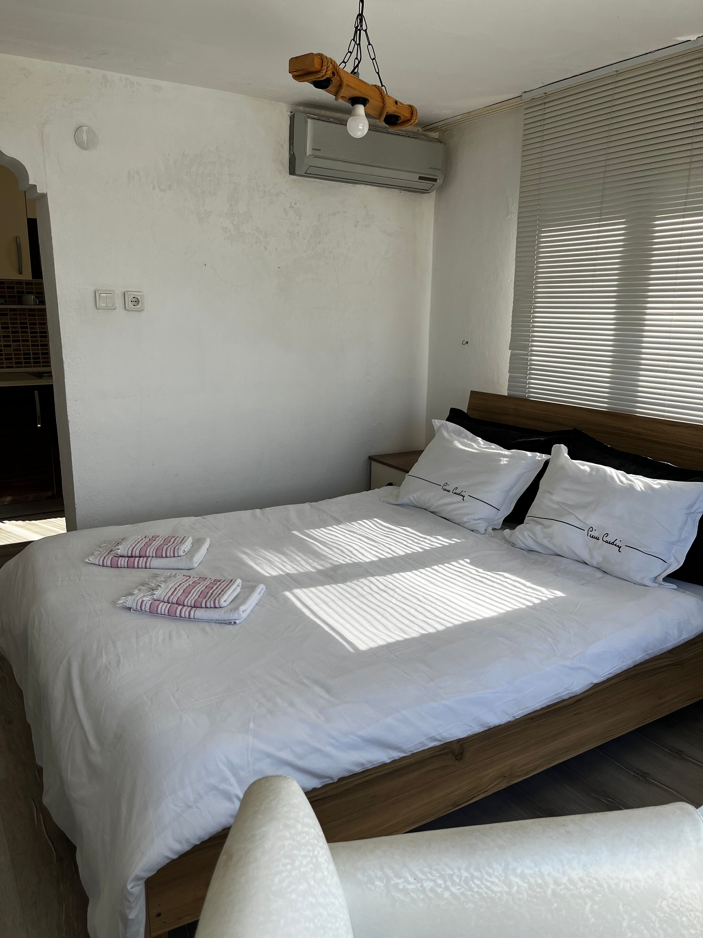 Une chambre à coucher avec un lit en bois, du linge de lit blanc et un ventilateur de plafond.