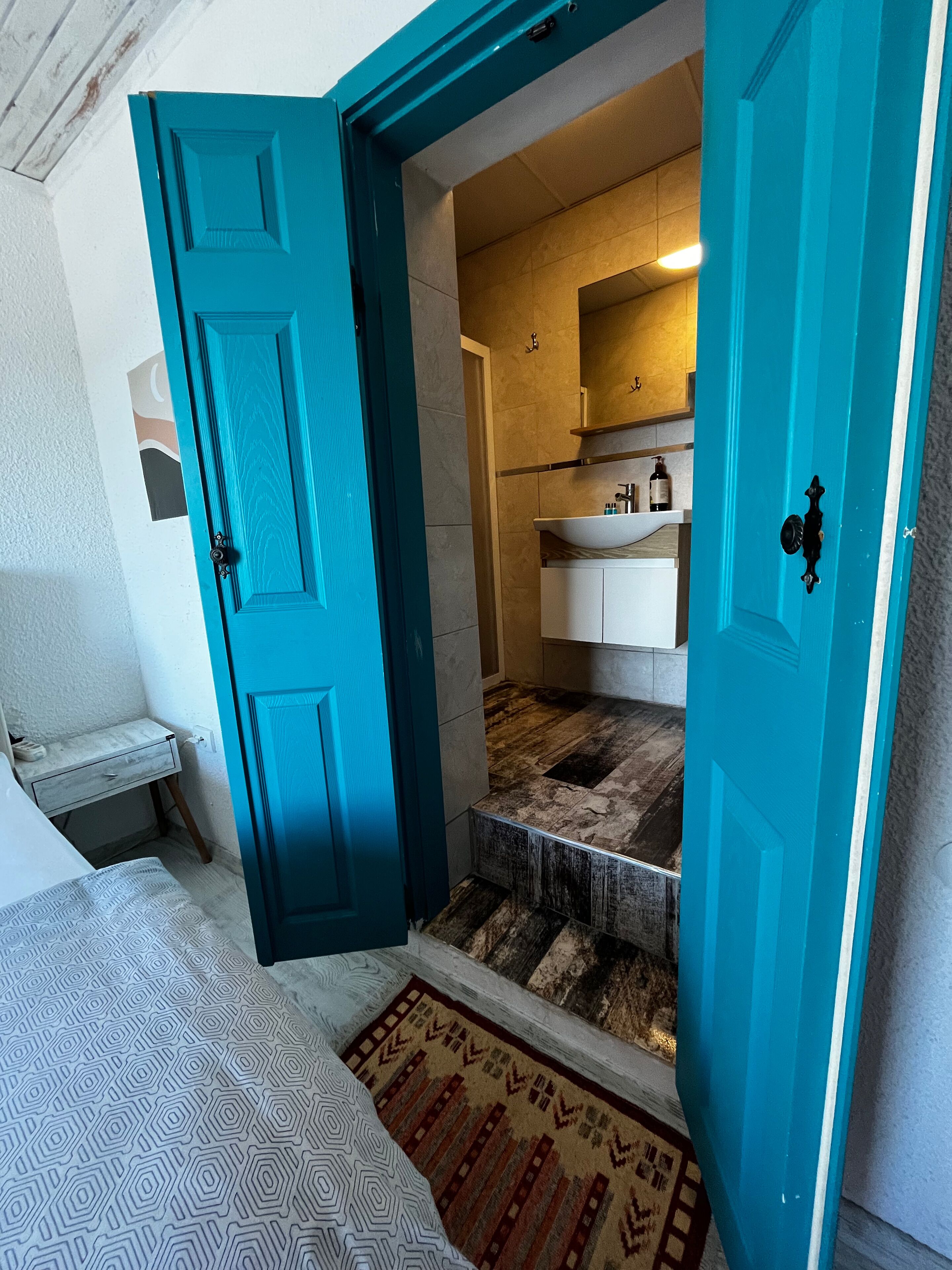 Un baño con lavamanos, espejo y perchero para toallas.