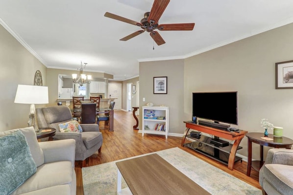 A living room with a ceiling fan, a television, and a bookshelf.