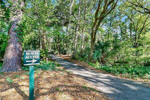 A forested path with a sign indicating beach access to the right.