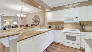 A modern kitchen with white cabinetry, granite countertops, a built-in oven, and a microwave. - 145 Colonnade Club Villa Beach Path, Pool, Hot Tub (Hilton Head Island)
