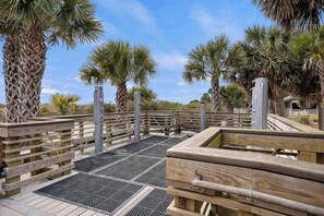 A wooden boardwalk with palm trees, a metal railing, and a water feature. - 145 Colonnade Club Villa Beach Path, Pool, Hot Tub (Hilton Head Island)