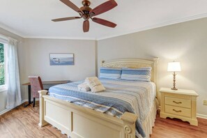 A bedroom with a bed, bedside table, lamp, and a ceiling fan.
