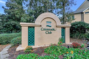 A sign for the Colonnade Club with a landscaped garden in front.