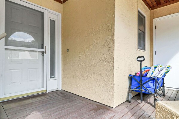 A covered porch with a door, a window, and a blue cart with items.