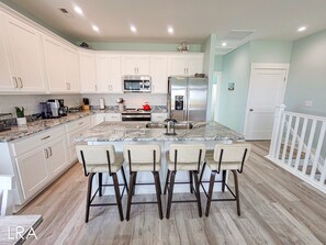 A modern kitchen with white cabinets, a granite countertop, and a central island with bar stools.