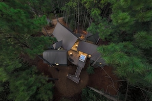 A cabin with a central deck, surrounded by dense forest. - Magical Luxury Treehouse! Epic Play Area! Bowling! (Broken Bow)