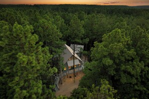 A secluded cabin surrounded by dense forest, featuring a prominent staircase leading to the entrance.