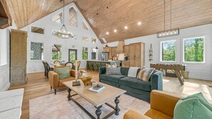 A spacious living area with a high ceiling, wooden beams, and large windows. - Luxury Treehouse! Elevated, Magical & Unique! (Broken Bow)
