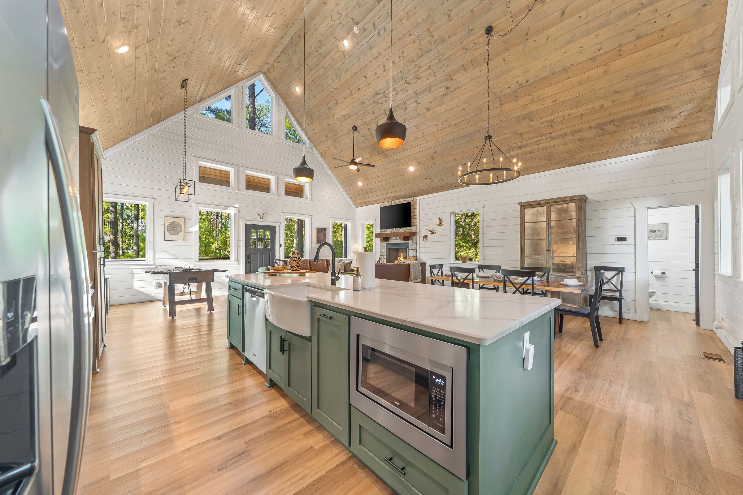 A spacious kitchen with a large island, wooden flooring, and a high ceiling with exposed beams.
