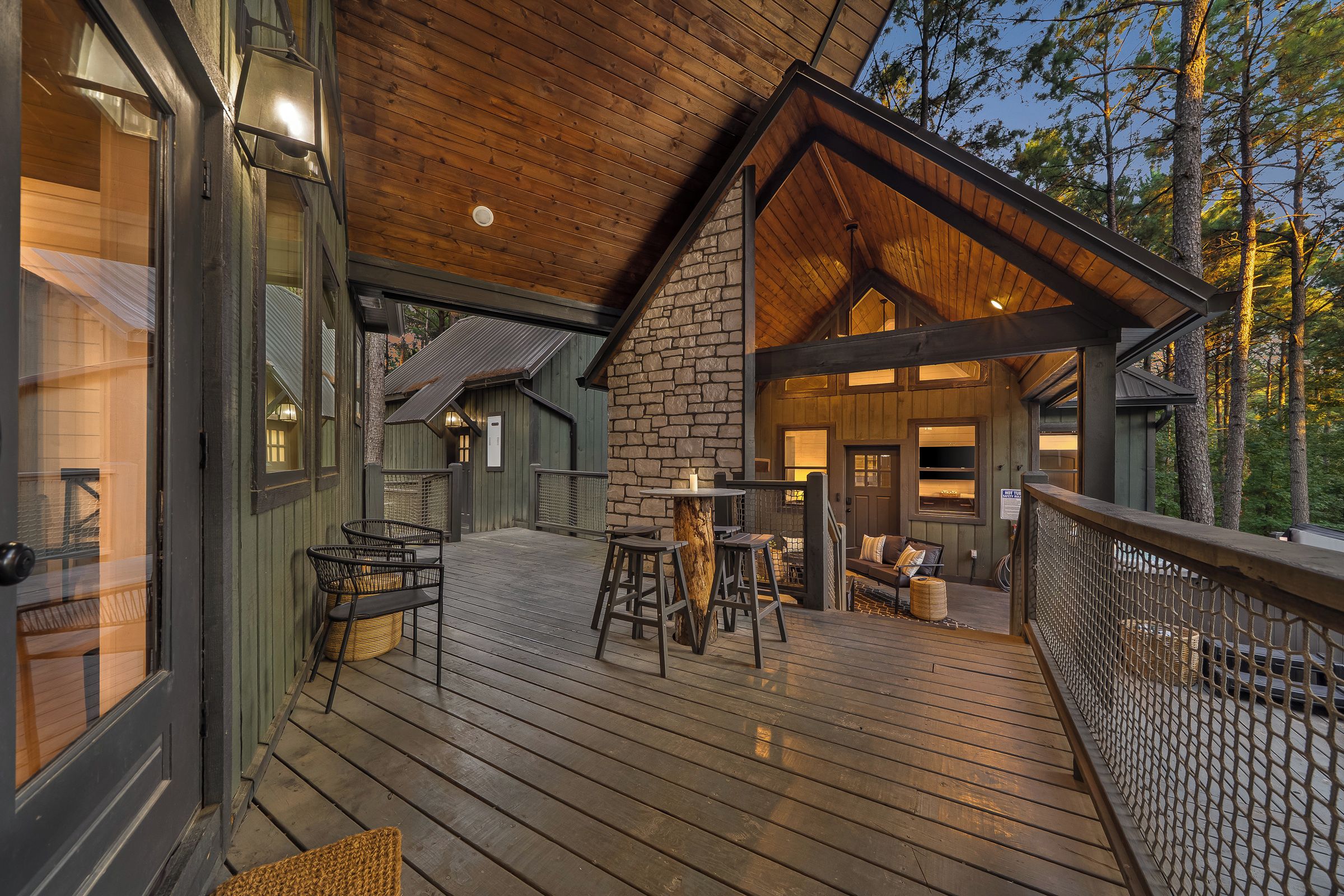 A wooden deck with outdoor seating and a stone fireplace.