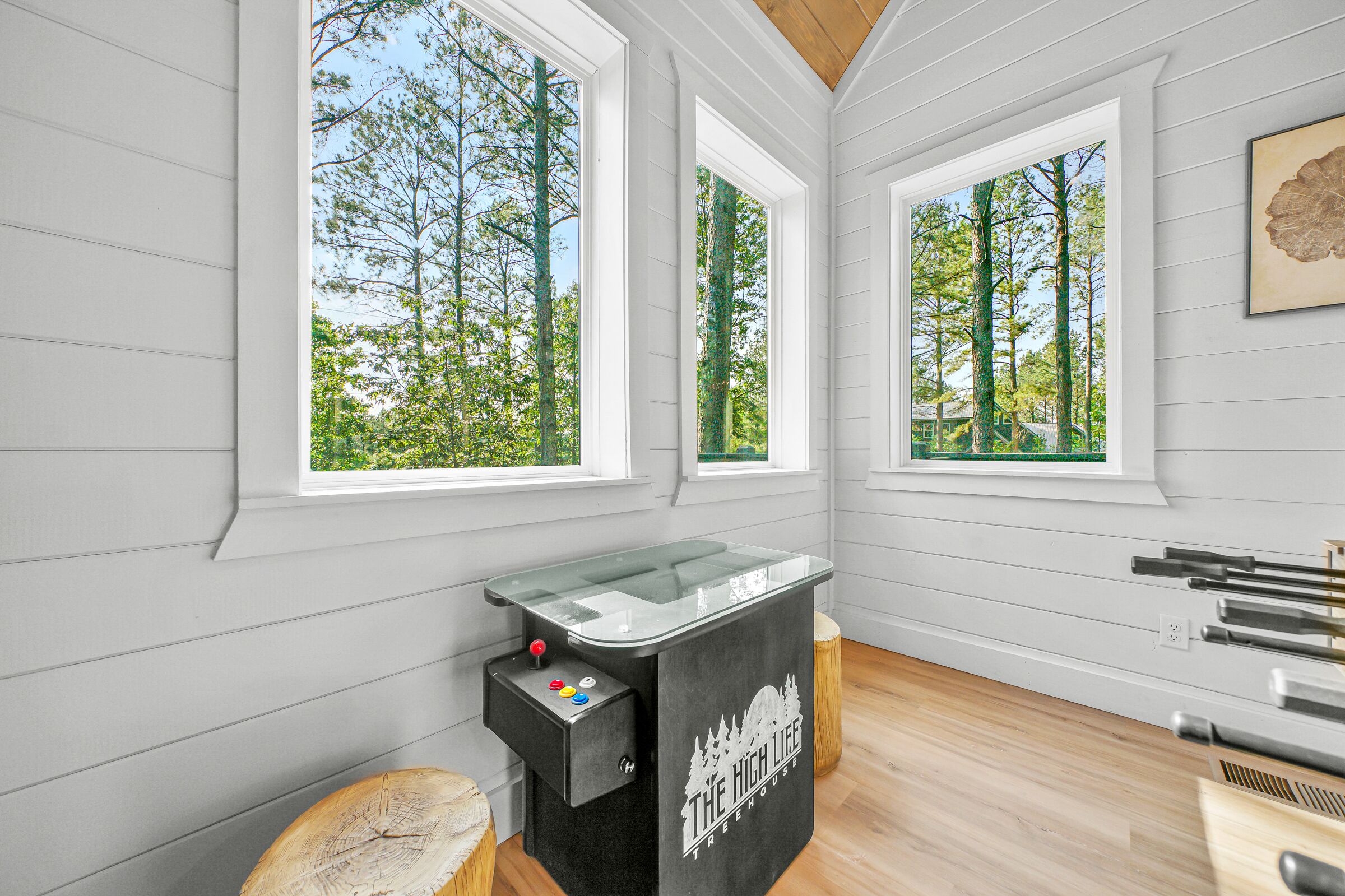 Una habitación con ventanas amplias, una mesa de billar y suelo de madera.