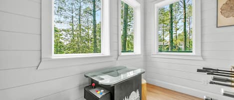 Una habitación con ventanas amplias, una mesa de billar y suelo de madera.