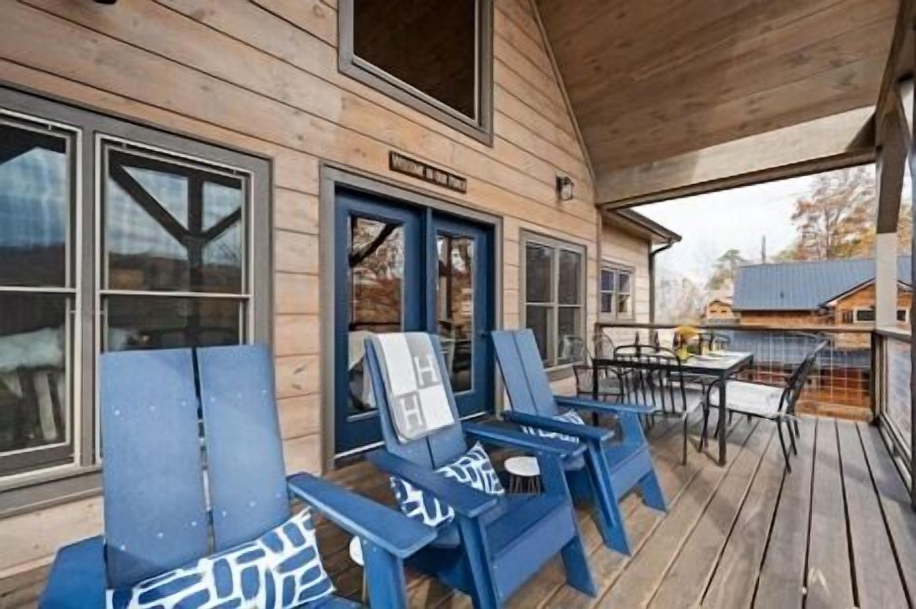 Un bâtiment en bois doté d’un porche couvert, d’un espace extérieur aménagé avec des chaises bleues, et d’une enseigne indiquant qu’il s’agit d’un restaurant.