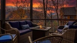 A cozy outdoor seating area with wicker furniture and a fire feature, overlooking a scenic landscape. - 🍃Serendipity Lodge🌲Mountain Views, Theater, Game Room & Pet-Friendly (Sevierville)