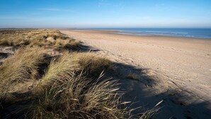 A sandy beach with dunes and a clear blue sky. - The Barn (Hunstanton)