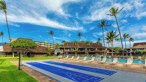 A pool area with shuffleboard, lounge chairs, and palm trees. - Ma'alaea Surf #G-2 – Relaxing Ground-Floor Getaway (Kihei, Maui)