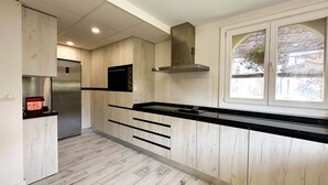 Een moderne keuken met houten lambrisering, een inbouwoven en een raam met uitzicht.