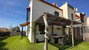 Een huis met een patio, een rieten dak en een kleine tuin.