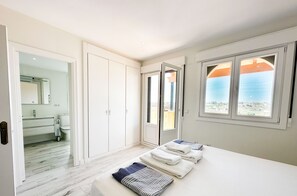 Une chambre avec un lit, une salle de bain avec un miroir et une vue sur la mer par la fenêtre.