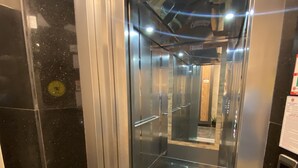 An elevator interior with a metallic finish, a digital floor indicator, and a reflective floor. - M-ODA OTEL (Antalya)