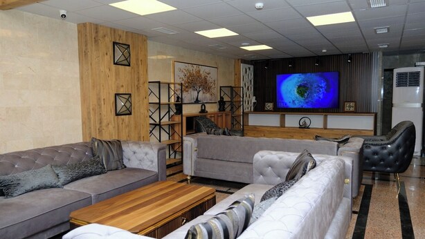 A modern living room with grey sofas, a wooden coffee table, and a large flat-screen TV mounted on the wall. - M-ODA OTEL (Antalya)