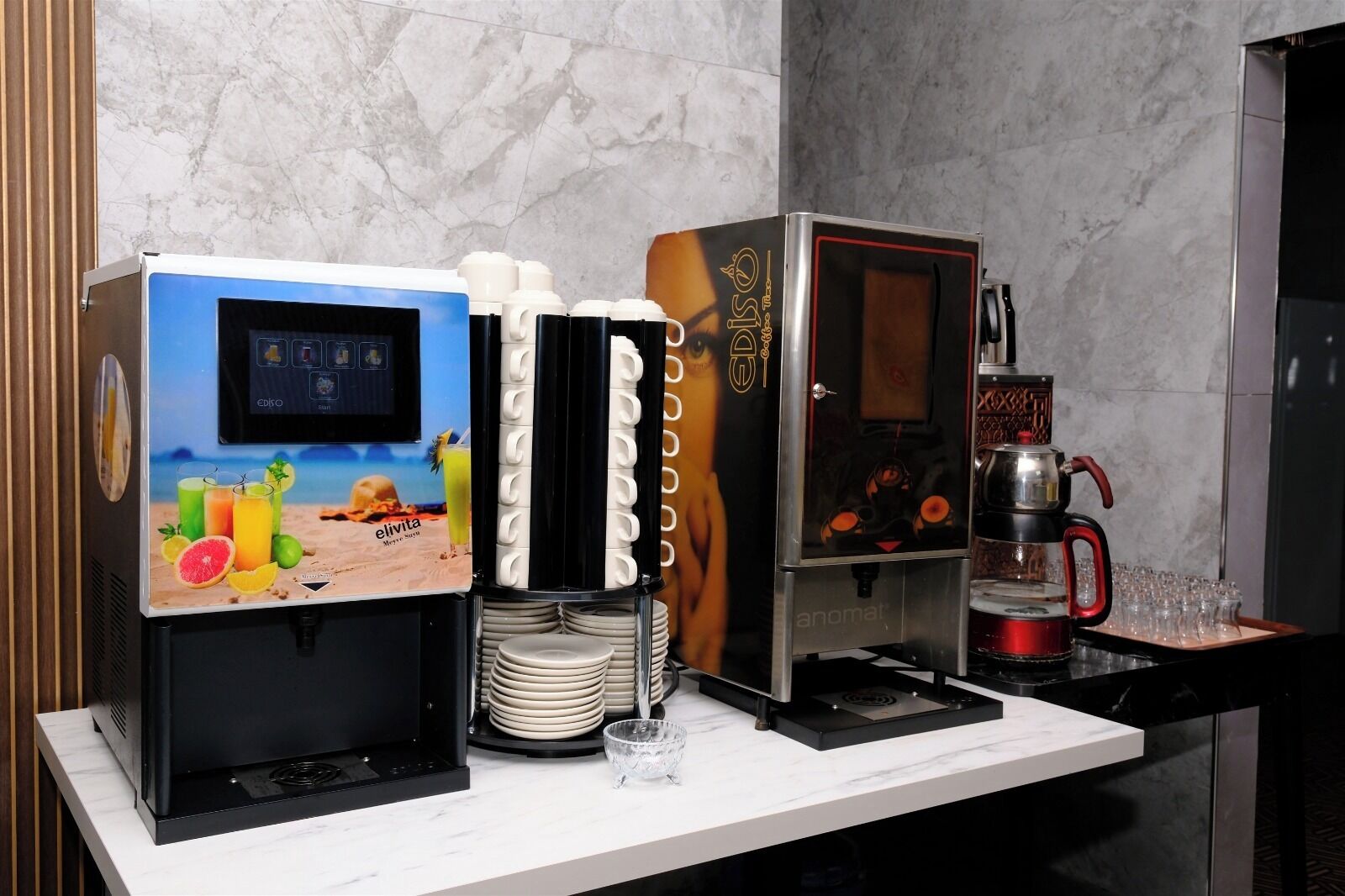 A coffee machine, a juice dispenser, and a coffee maker on a marble countertop.