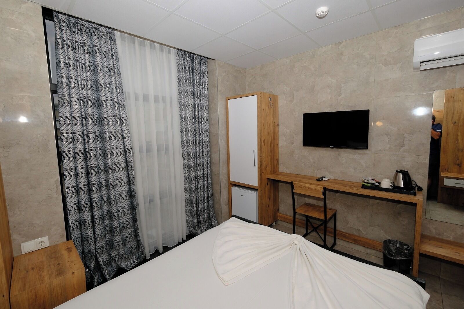 Ein Hotelzimmer mit Bett, Schreibtisch, Fernseher und Kleiderschrank.