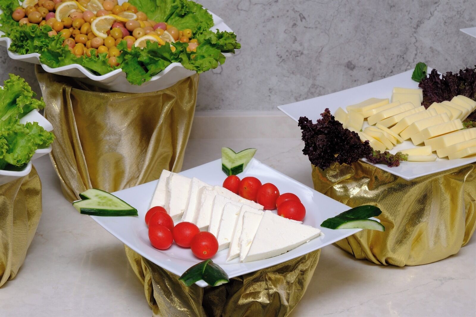 A variety of food items arranged on a table, including cheese, tomatoes, and leafy greens.