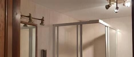 A bathroom with a shower, a sink, and a mirror.