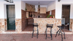 A kitchen with stone walls, a tiled backsplash, and a bar area with stools.