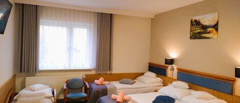 A hotel room with two beds, a chair, a desk, and a painting on the wall.