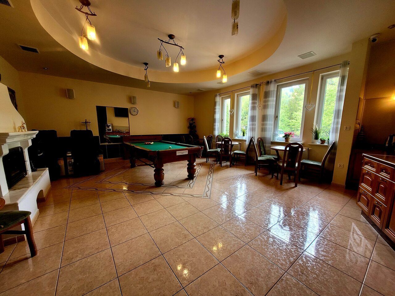 Una sala de billar con mesa de pool, sillas y chimenea.