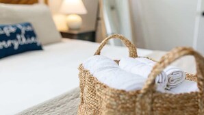 A bed with a blue pillow and a wicker basket containing rolled towels. - Historic NoDa Mill House • Steps to Shops & Dining (Charlotte)